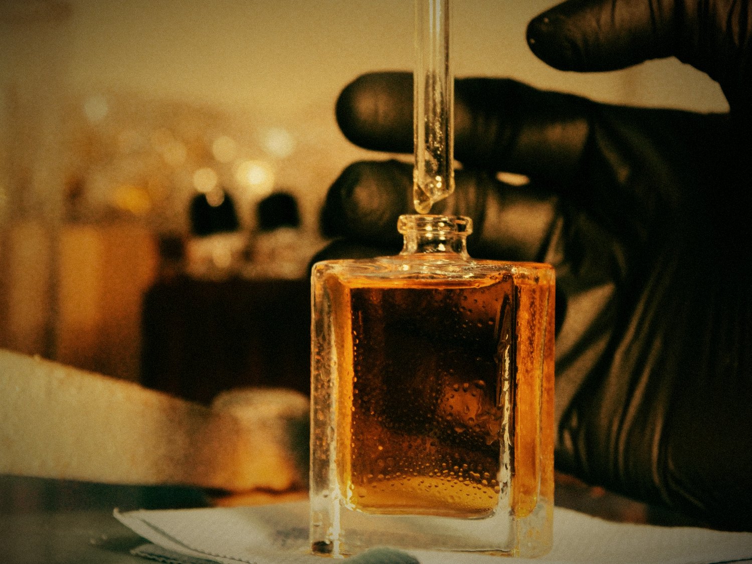 A gloved hand holding a filled flacon in the blending room