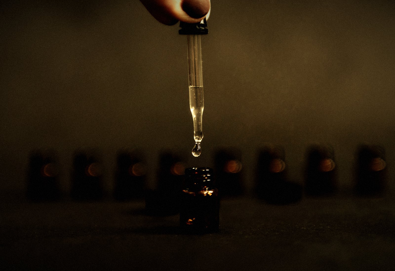 A pipette releasing essence into a row of amber vials